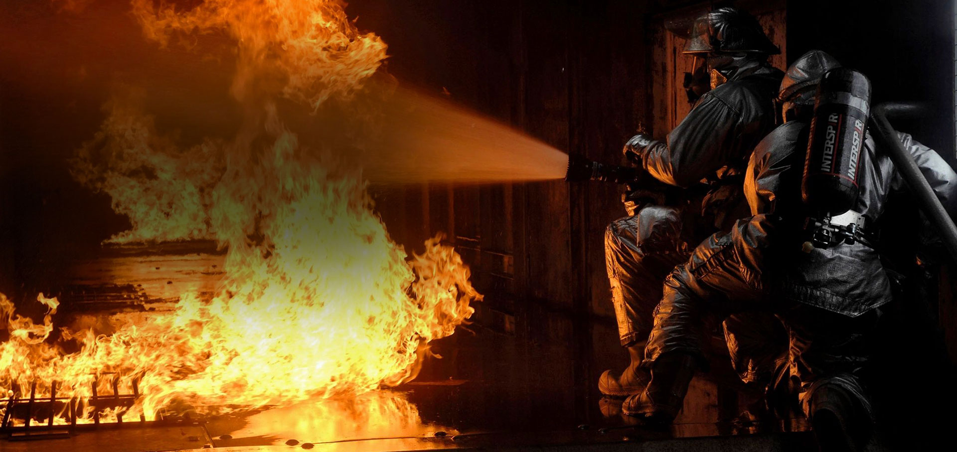 Firefighters working through heavy flames inside a burning home